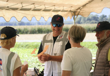 Un expert transmet le modèle de son projet (petit avion) à son successeur, symbolisant la formation, l'audit des processus et la pérennité de l'entreprise.